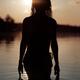Dark silhouette of a woman coming out of the water after bathing in a... (thumbnail)