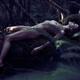 Beautiful nude woman with wet shiny body lying naked on a mossy tree t... (thumbnail)
