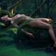 Beautiful nude woman with wet shiny body lying naked on a mossy tree t... (thumbnail)