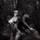 Beautiful nude woman leaning against a tree trunk in a forest with sun... (thumbnail)