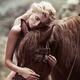 Beautiful naked woman with blond hair hugging a brown horse in the nat... (thumbnail)