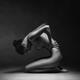 Artistic nude side view of a woman sitting naked curled up in studio w... (thumbnail)