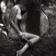 Beautiful nude woman sitting in a tranquil nature scenery leaning agai... (thumbnail)