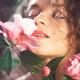Closeup of a beautiful sensual young woman with red lips smelling pink... (thumbnail)
