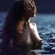 Woman with long curly hair standing topless in reflective water of a l... (thumbnail)