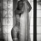 Sexy young woman in white lace lingerie and stockings standing with he... (thumbnail)