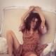 Sexy girl in bohemian dress sitting on a sofa with a sensual provocati... (thumbnail)