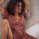Sexy young woman in boho dress sitting relaxed on a sofa in a sensual... (thumbnail)