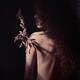 Abstract mysterious portrait of a bare shoulder of young woman holding... (thumbnail)