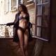 Woman in sexy lingerie under her open trench coat standing by an open... (thumbnail)