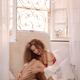 Young woman in white underwear relaxing by an open sunlit window in vi... (thumbnail)