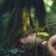 Face of a woman lying on green moss in a forest covering her naked bod... (thumbnail)