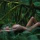 Nude woman lying in a dark green mossy forest nature scenery caressing... (thumbnail)