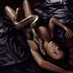 Beautiful sexy woman lying on silky bed in ecstatic pose with large Ku... (thumbnail)