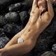 Beautiful nude woman lying on rocks in water with sea shell barely cov... (thumbnail)