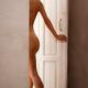 Figure of a young woman walking naked through a doorway entering a bat... (thumbnail)