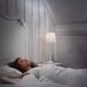 Woman sleeping in bed alone in white vintage room with a book and a la... (thumbnail)