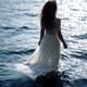 Woman in sheer white dress standing in the water in sunshine... (thumbnail)