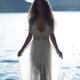 Woman in sheer white lace dress walking out of sea water in bright sun... (thumbnail)