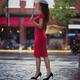 Woman in elegant red dress waiting for someone on a city street with a... (thumbnail)