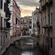 Historic old buildings and a foot bridge over a waterway at sunset in... (thumbnail)