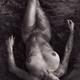 Beautiful nude woman lying in dark water relaxed with closed eyes view... (thumbnail)