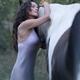 Expressive portrait of a beautiful young woman hugging a black horse w... (thumbnail)