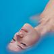 Beautiful young woman face lying half submerged in turquoise blue wate... (thumbnail)