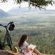 Girl sitting on a blanket with a book and a bike enjoying a little pic... (thumbnail)