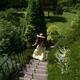 Young woman in summer dress and hat running down the stairs in a green... (thumbnail)