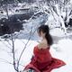 Beautiful young woman in red kimono sitting in snow by a frozen river... (thumbnail)