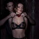 Sensual couple suggestive portrait of man tying choker around neck of... (thumbnail)