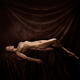 Fine art nude photograph of a beautiful woman lying naked posing in ar... (thumbnail)
