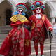 Brightly dressed couple in oriental red costumes and masks during the... (thumbnail)