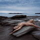 Beautiful nude young woman lying naked stretched on ocean shore rock i... (thumbnail)