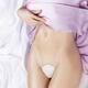 Sexy half-nude woman with sensual curves lying on white satin bed with... (thumbnail)