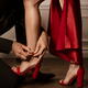 Sexy woman legs in red high-heel sandals and a man fastening the shoe... (thumbnail)