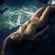 Young nude woman with beautiful wet sexy naked body lying on rocks by... (thumbnail)