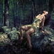Beautiful young woman sitting on a rock in a forest in a sensual relax... (thumbnail)