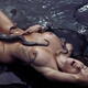 Beautiful woman making love to a giant octopus lying on sea shore with... (thumbnail)