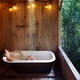 Woman lying naked relaxed in open-air bath tub in a rustic countryside... (thumbnail)