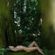 Beautiful nude woman lying tied up with bondage ropes on mossy tree tr... (thumbnail)