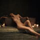 Beautiful nude woman leaning gracefully against a stone bath with cand... (thumbnail)