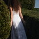 Young lady in white summer dress walking into a green garden disappear... (thumbnail)