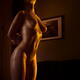 Beautiful nude woman with shiny golden skin leaning against a wooden p... (thumbnail)