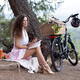 Young pretty woman sitting on a blanket with book and bike enjoying a... (thumbnail)