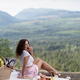 Young woman in cute pink mini skirt having picnic in the nature biting... (thumbnail)