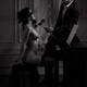 Gentleman caressing with a rose a gorgeous woman sitting at a piano na... (thumbnail)