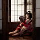Beautiful caucasian lady, Japanese geisha sitting with hand fan in a s... (thumbnail)