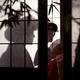 Beautiful caucasian lady geisha with hand fan behind shoji screen of t... (thumbnail)